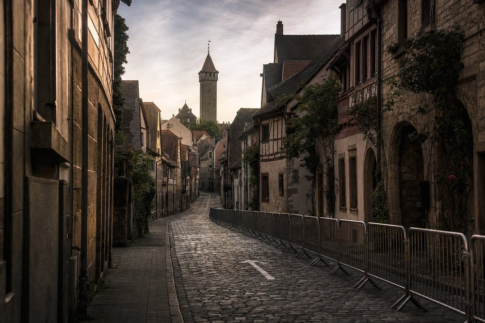 Enge, kopfsteingepflasterte Gasse in der Friedberger Altstadt am frühen Morgen mit Absperrungen für einen Stadtlauf, im Hintergrund der hohe Adolfsturm